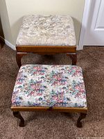 Two floral upholstered footstools on carpet
