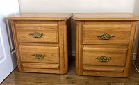 Front view of both oak nightstands showing drawers and brass pulls