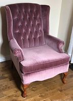 Full view of pink velvet wingback chair angled