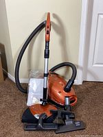 Full view of vacuum with hose, wand, attachments, and bag pack