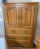 Front view showing two doors and three drawers with brass pulls