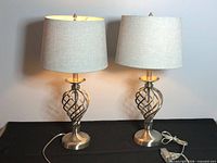Front view of both matching silver twisted base table lamps with grey shades