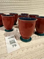 Eight red and teal Denby coffee cups on textured surface
