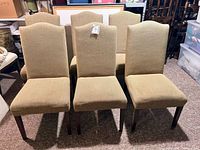 Front view of six beige upholstered dining chairs