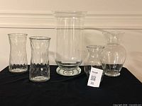 All five clear glass vases displayed together on black surface