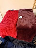 Red cable knit and brown plush throw blankets side by side