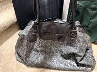 Bueno duffle in foreground with black Leisure suitcase and green Jaguar suitcase partly visible