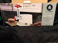 Retail box showing Hometrends 2400-W electric meat grinder and accessories