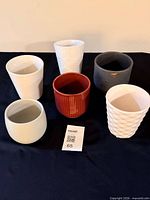 Six assorted small ceramic planters on black surface, overhead view