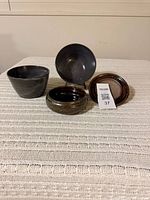 Two bowls, container body and lid arranged to show shapes and makers marks