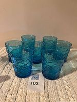 seven blue glass tumblers grouped on cloth