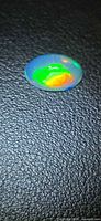 Oval Ethiopian crystal opal showing vivid green and orange flash