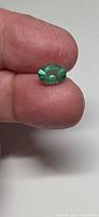 Emerald held between fingers showing size and faceting