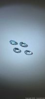 Four light blue oval faceted aquamarine stones on neutral background