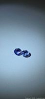Pair of round violet-blue Tanzanites on neutral background