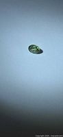 Top view of loose oval faceted green sapphire on white background