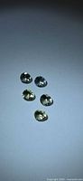 Five faceted round gemstones in two color groups on neutral background