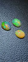 Three oval opal cabochons showing body colour and play-of-colour on black background
