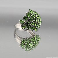 Oblique view of sterling silver ring showing cluster of green stones and reflective band