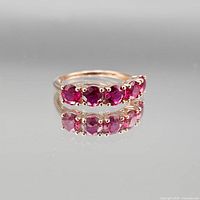 Front view of ring showing five round pink/red stones and rose gold finish