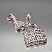 Front view of sterling silver padlock and key charms with pavé stones