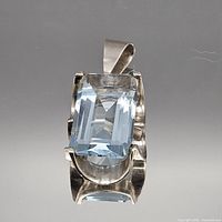 Front view of sterling silver pendant showing light blue rectangular faceted stone and bail