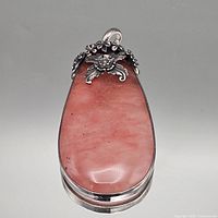 Front view of sterling silver pendant with pink cabochon and floral bail