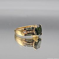 Oblique view of yellow-gold tone sterling silver ring with round green center stone and shoulder accent stones