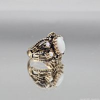 Three-quarter view of sterling silver opal ring showing filigree detail and cabochon stone
