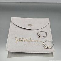 pair of two-tone hoop earrings on John Medeiros pouch
