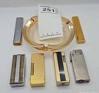 Group shot of six lighters and amber glass ashtray