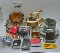 Group shot showing all lighters, ashtrays, Wedgwood pieces, flints