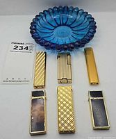 Group shot of six lighters and blue glass ashtray