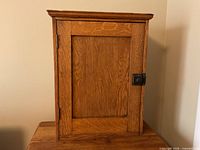Front view of wooden cabinet on table showing latch and hinges