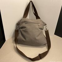 Front view showing grey canvas, brown strap, exterior zip pocket
