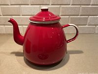 Side view of red enamelware tea kettle with lid