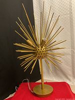 Full view of gold-toned Sputnik ceiling light on base showing radiating rods and wiring