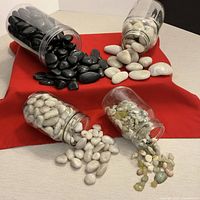 Four jars tipped showing contents: black, white, off-white, mixed pebbles