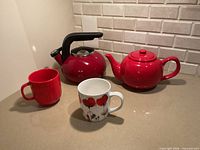 Group shot of kettle, teapot, red mug and poppy mug on countertop