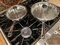 Both pans on stovetop showing size difference and handles