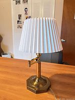 Lamp unlit showing brass base, swing arm and white pleated shade