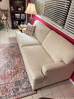 Full view of beige Bassett sofa against pink wall