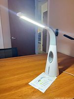 Lamp illuminated on desk showing LED arm and base