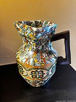 Front view showing mosaic pattern, floral band, square handle