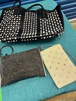 All three bags displayed: black studded handbag, black rhinestone clutch, cream heart-stud clutch