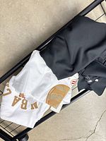 White 2019 Champions t-shirt and black Raptors tee folded on cart