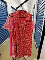 Red sleeveless dress and partial view of pink dress on rack