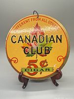 Front of circular Canadian Club cigar sign on stand