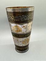 full view of engraved metal lassi cup showing gilt floral bands and tapered form