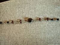 Full view of bracelet laid flat showing chain strands, onyx cabochon and garnet beads